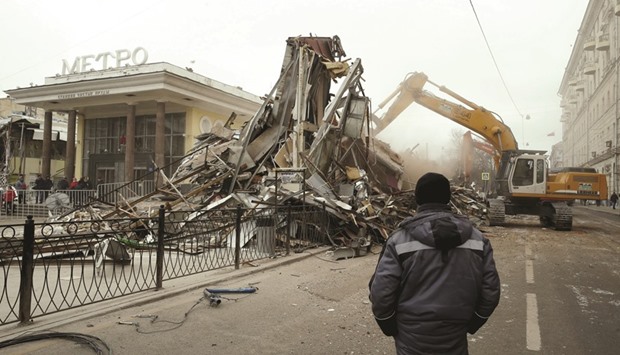 A man watches as an excavator is used to demolish illegal street kiosks and stalls near Chistiye Prudy metro station in Moscow.