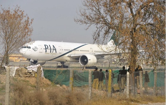 Policemen stand guard as a PIA plane taxis on the runway on the way to Saudi Arabia in Islamabad.