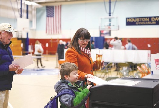 A woman with a child casts her ballot for the presidential primary at a school gym in Concord, New Hampshire.