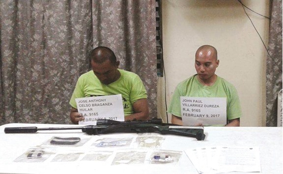 Drug suspects John Paul Dureza and Jose Anthony Huilar are shown in a picture released yesterday, with weapons, u201cshabuu201d in sachets and peso bills, after they were arrested in a buy bust operation by agents of Philippine Drug Enforcement Agency in Davao city in southern Philippines yesterday.