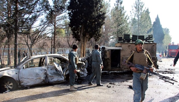 Afghan policemen inspect a damaged army vehicle after a suicide attack in Lashkar Gah, Helmand province, Afghanistan.