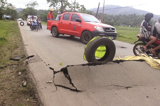 Vehicles pass cracks on a road that appeared along the National Highway at Rizal town after an earthquake hit Surigao city, southern Philippines yesterday.