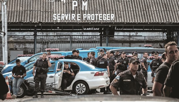 Police officers wait as their relatives block the entrance to the military police station during a protest for better salaries and working conditions in Rio de Janeiro.