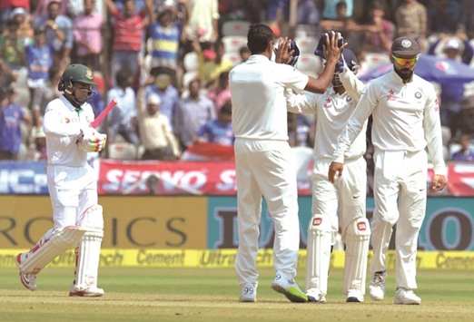 Bangladeshu2019s Mushfiqur Rahim (left) walks off the field as Indian players celebrate his wicket on Day Four of the one-off Test in Hyderabad yesterday. Captain Rahim scored 127 in the first innings before Bangladesh were bundled out for 388. (AFP)
