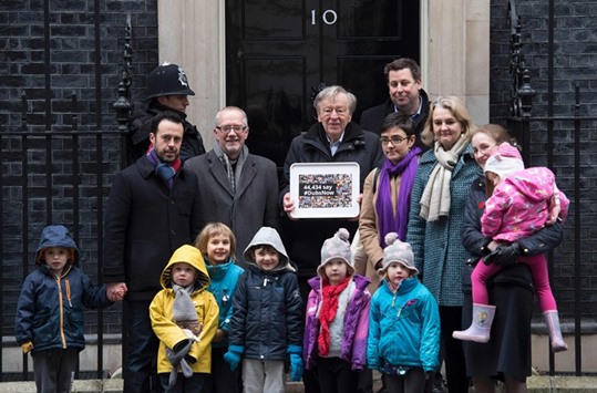 Lord Alf Dubs (C) poses for journalists with supporters outside 10 Downing Street in London before handing in a petition calling on the prime minister to reconsider the decision to close the u2018Dubsu2019 scheme to take refugee children into the UK.