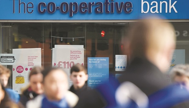 People walk past a branch of the Co-operative Bank in London. The bank said yesterday that it had made considerable progress implementing a turnaround plan, cutting its cost base by a fifth since 2014, but it still expects to make a u201csignificant lossu201d for last year.