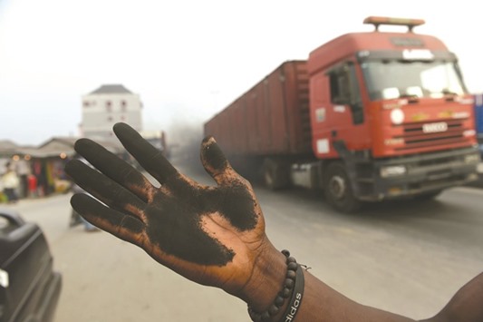 A man holds out his soot-covered hand yesterday to illustrate how much soot covered the bonnet of his car in Port Harcourt.