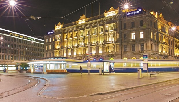 A tram passes the illuminated headquarters of Credit Suisse Group in Zurich. Credit Suisse plans to cut as many as 6,500 jobs this year and is keeping its options open as it prepares for a partial sale of its Swiss unit to strengthen capital.