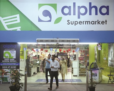 People walk out of the Alpha Supermarket under which Tesco products will be stocked in Karachi.