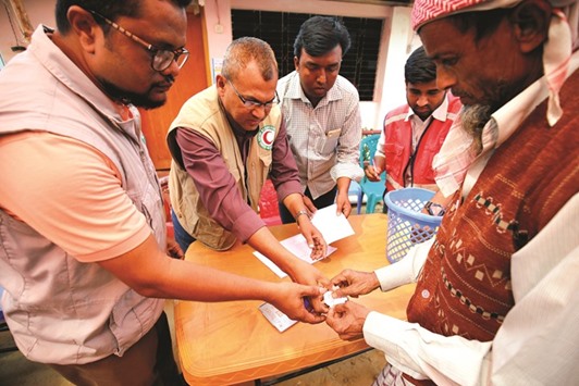 Volunteers of the Bangladesh Red Crescent Society check the voucher of a Rohingya refugee prior to handing over relief, including food and medicine, sent from Malaysia at Kutupalang Unregistered Refugee Camp in Coxu2019s Bazar.