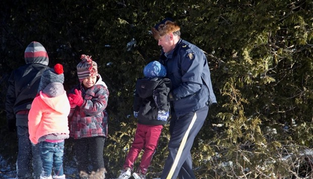 A Royal Canadian Mounted Police (RCMP) officer assists a child and family that claimed to be from Sudan as they walk across the US-Canada border into Hemmingford, Canada, from Champlain in New York, US.