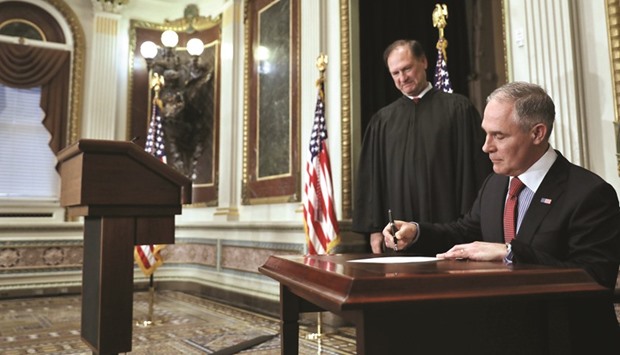 Pruitt signs a document after his swearing-in ceremony, presided by Justice Samuel Alito (left), at the Executive Office in Washington.