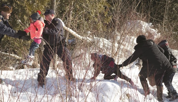 RCMP officers assist a child from the family after they ran across the border into Hemmingford, Canada, from Champlain in New York, US.