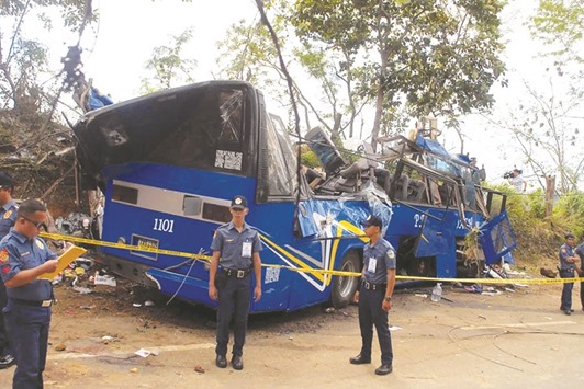Police and soldiers stand guard next to a tourist bus which hit an electric post in Tanay town, Rizal province, east of Manila yesterday.