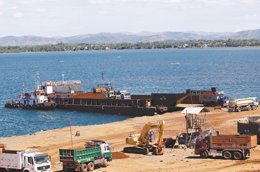 A port is pictured as trucks and a back hoe load rocks and soil containing nickel-ore minerals into a barge in the mining town of Sta Cruz Zambales in northern Philippines.