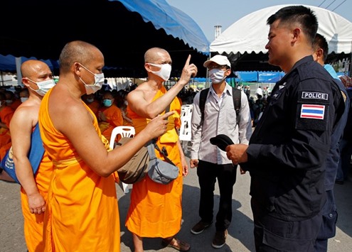 Buddhist monks speak with a policeman at the gate of Dhammakaya temple in Pathum Thani province, Thailand.