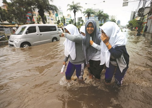 Students wade through floodwaters after school in a flood-hit area at the Mangga Dua business district in Jakarta, Indonesia.