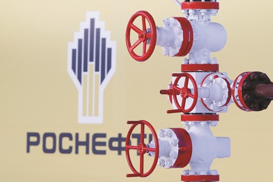 The logo of Russian state oil company Rosneft is seen behind a pipe at the Samotlor oil field in Nizhnevartovsk, Russia. The firm agreed to invest in exploration and production in Libya, the state-run National Oil Corp said yesterday.