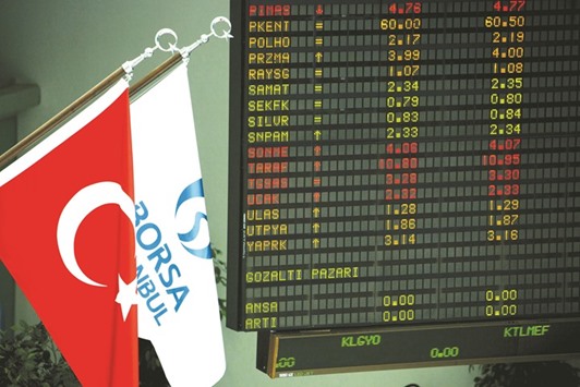 The Turkish national flag (left) and the Borsa Istanbul flag hang alongside financial data displayed inside the Borsa Istanbul (file). Turkeyu2019s gold reserves have tripled since late 2011.