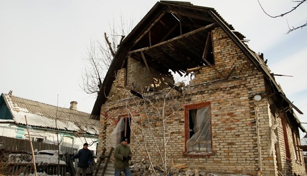 Men walk near a damaged house following shelling in Makeyevka