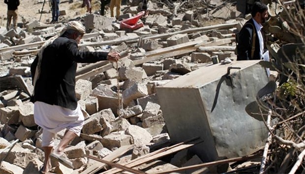 People walk on the rubble of a house destroyed by a Saudi-led air strike in Sanaa on Thursday.