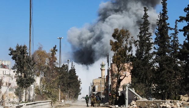 Opposition fighters backing Turkish troops gather on a road as smoke billows following an air strike on an Islamic State (IS) group position on February 21, 2017, in the Syrian town of al-Bab.