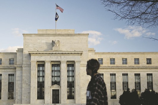 A pedestrian walks past the Federal Reserve building in Washington, DC. For all the preoccupation in the bond market about the fate of the Fedu2019s $2.46tn portfolio of Treasuries, officials may ultimately be hard-pressed to pare down holdings amassed as part of the biggest economic stimulus programme in history.