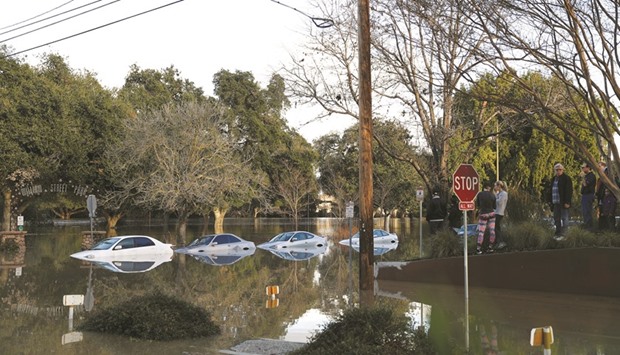 Flood waters flow around partially submerged vehicles at William Street Park, near Coyote Creek in San Jose.