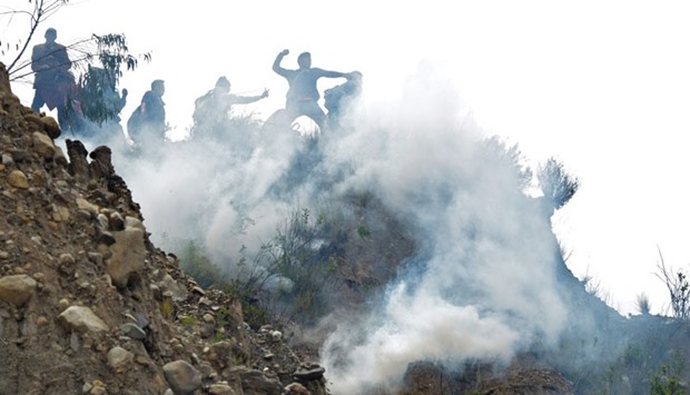 Bolivian coca growers from Los Yungas region confront riot police agents within a tear gas cloud, during a protest against a bill that caps legal coca crops extensions in La Paz.