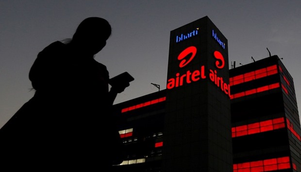 A girl checks her mobile phone as she walks past the Bharti Airtel office building in Gurugram, previously known as Gurgaon, on the outskirts of New Delhi.