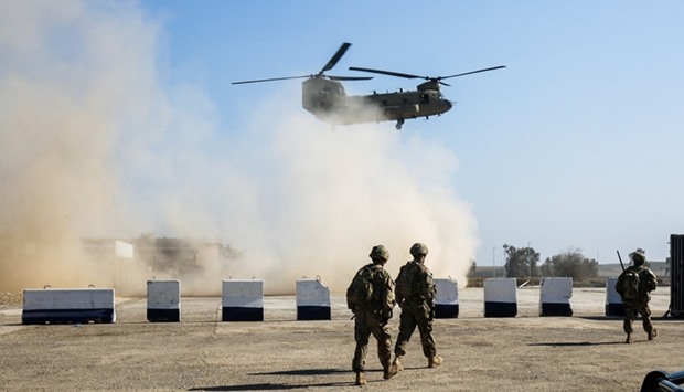 US troops walk as a US C-47 Chinook helicopter flies over the village of Oreij, south of Mosul, on February 22, 2017, where a temporary military base has been established for an assault on the city's west bank. Iraqi forces readied on February 22, 2017 for an assault on Mosul airport after blitzing jihadist positions in a renewed offensive to retake the Islamic State group's emblematic stronghold.