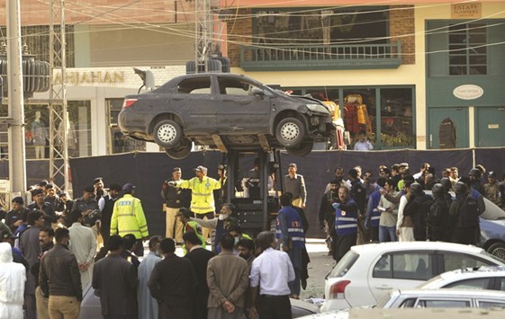 Pakistani officials move a damaged car from the site after a bomb attack in Lahore yesterday.