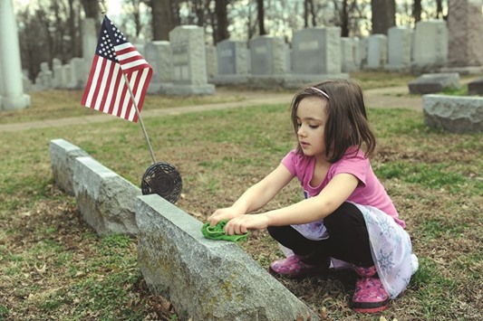 A child cleans a headstone during a clean-up effort on Wednesday at the Chesed Shel Emeth cemetery in University City, Missouri.