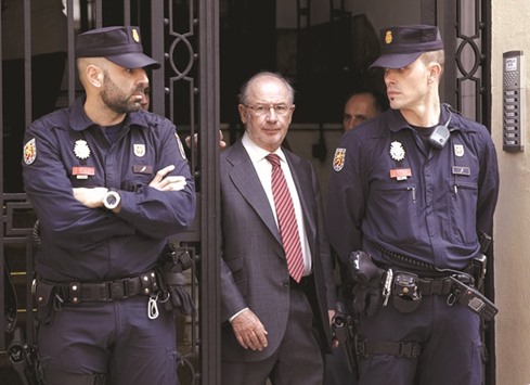 Former International Monetary Fund chief Rodrigo Rato (centre) walks between police officers as he leaves his office in Madrid April 17, 2015. Rato was handed a jail sentence of four years and six months yesterday for misusing funds when he was the boss of two Spanish banks.
