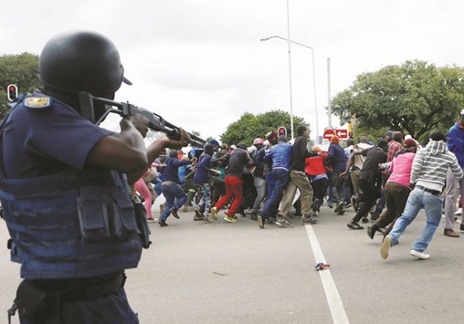 A South African officer aims to fire rubber bullets to disperse Somali and foreign nationals clashing with South African nationals during the protest march against illegal immigrants yesterday.