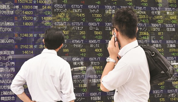 Pedestrians look at a share prices board in Tokyo. The Nikkei 225 closed down 0.5% to 19,283.54 points yesterday.