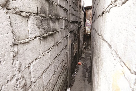 A small alley is pictured before a door on the far end left leading to a drug den in Manila.