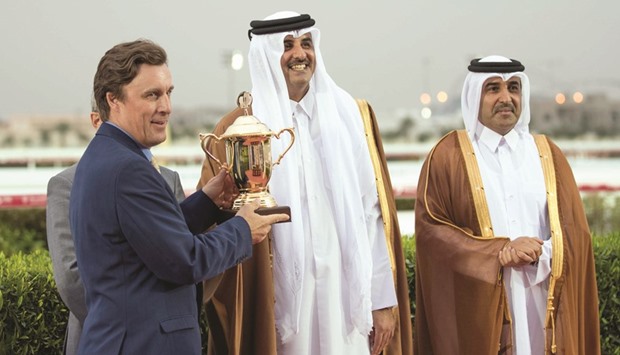 HH the Emir Sheikh Tamim bin Hamad al-Thani (centre) presents Julian Smart (left) with the traineru2019s trophy after Ebraz, owned by HH Sheikh Mohamed bin Khalifa al-Thani, won the HH The Emiru2019s Sword (Gr1 PA) at the Qatar Racing and Equestrian Club yesterday. Also seen is QREC chairman Issa al-Mohannadi.