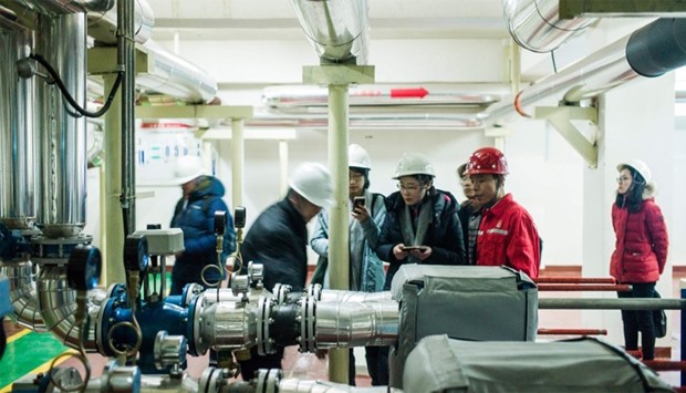 A worker from Sinopec Company, showing how the heat pump is operated to journalists in Zangangzhen