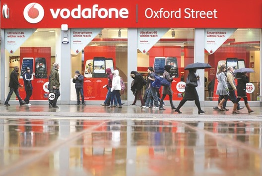 Pedestrians walk past a Vodafone Group store on Oxford Street in London. Telecom executives from Vodafone to Deutsche Telekom and Telefonica are headed to the industryu2019s annual get-together in Barcelona this week with more on their minds than the latest handsets.