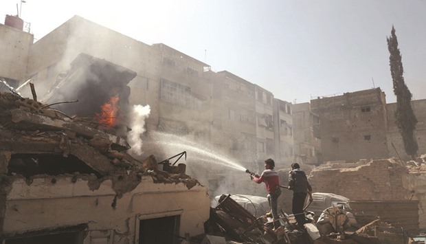 Syrian men and Civil Defence volunteers, also known as the White Helmets, extinguish fire following a reported government air strike on the rebel-held town of Douma, on the eastern outskirts of the capital Damascus yesterday.