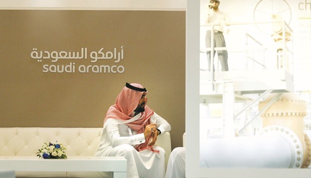 An Aramco employee sits in the area of its stand at the Middle East Petrotech 2016 in Manama. An industry source familiar with the matter says Aramco will buy a stake in RAPIDu2019s refinery, cracker and petrochemical operations. It will also supply at least 50% of the crude that will be processed at RAPID, with an option to increase the supply, the source said.