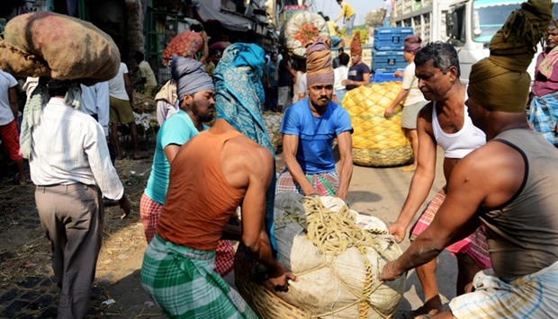 Indian labourers carry baskets of vegetables at the main wholesale vegetable market in Kolkata.