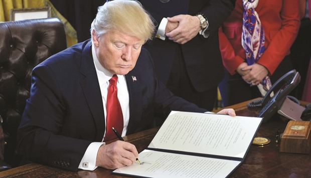 Trump signs the executive order directing the Treasury Secretary to review the Dodd-Frank financial oversight law in the Oval Office.
