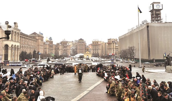 People kneel during obsequies on Kievu2019s Independence Square as servicemen carry a coffin with the body of a Ukrainian soldier who died during fighting in the eastern Ukrainian town of Avdiivka.