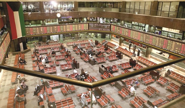 Traders follow share prices at the Kuwait Stock Exchange in Kuwait City (file). The latest Reuters poll showed fund managers deeply split on the market, with 38% expecting to raise their allocations there and 38% expecting to reduce them.