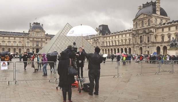 Journalists stand in front of the Louvre Pyramid yesterday.