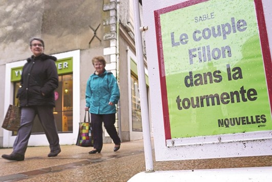 A resident walks past a billboard showing the headlines of the newspaper Les nouvelles de Sable reading u2018Fillon spouses in turmoilu2019 in Sable-sur-Sarthe, northwestern France.