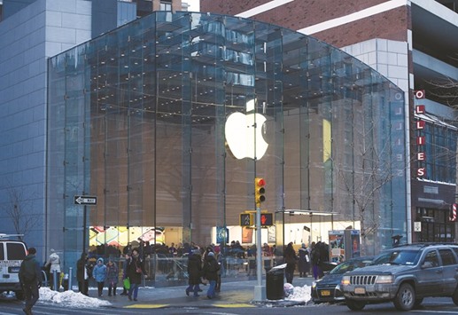 Pedestrians pass in front of an Apple store in New York. Apple is boosting the prices of iPhones sold abroad by as much as 40% to offset the declining value of foreign sales when theyu2019re converted to dollars.