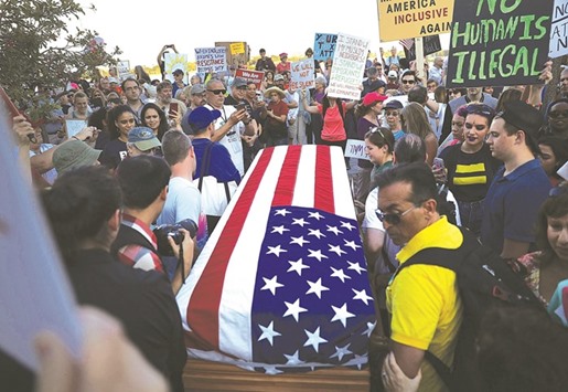 A flag-draped coffin symbolising the death of democracy is carried by protesters as they walk to where Trump is staying, at Mar-a-Lago Resort, Palm Beach, Florida. Trump is on his first visit to Palm Beach since his inauguration.